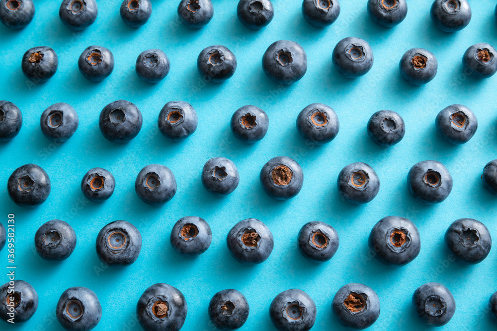 Blueberry pattern on blue background. Ripe blueberries texture close up.