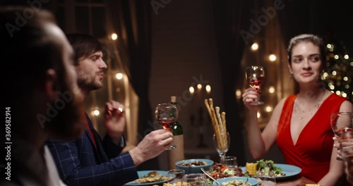 Happy friends celebrating christmas or graduation together, having a dinner party, clinking thir glasses with wine, talking and smiling - celebration, real people 4k footage photo