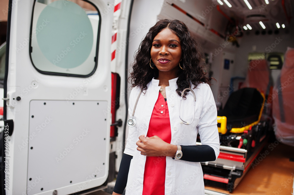 African american female paramedic standing in front of ambulance car. African american female paramedic standing in front of ambulance car.