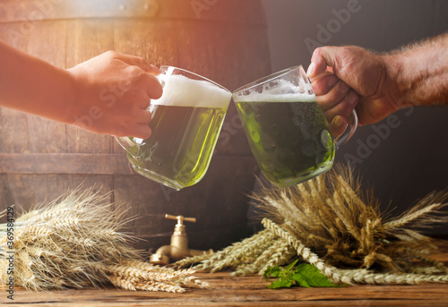 Green beer in the hands of two friends. In the background is woodenoak barrel. photo