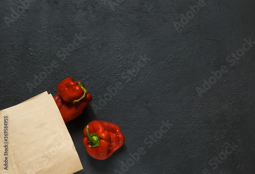 Two ugly red peppers with a paper bag on a black background with space photo