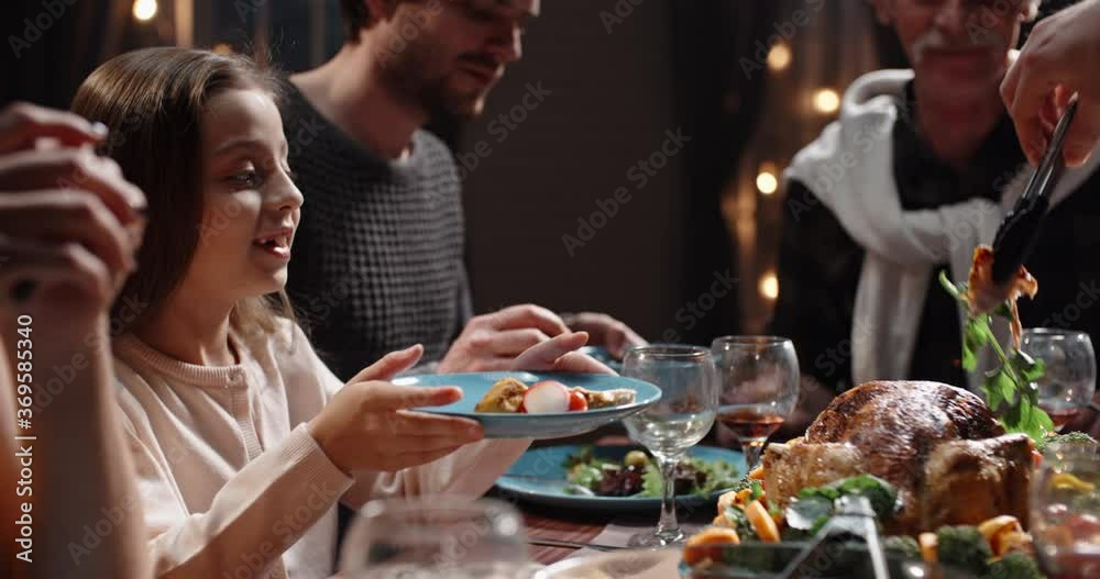 Large caucasian family celebrating thanksgiving day, chatting at dinner party table while eating roasted turkey and salads - celebration concept 4k footage