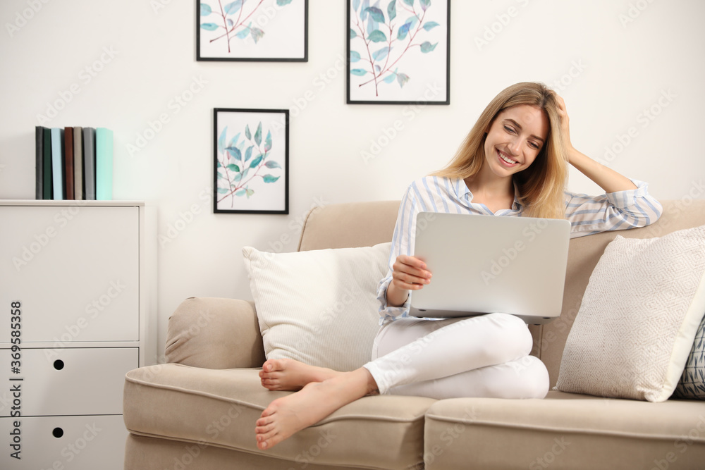 Pretty young woman with laptop sitting on sofa at home Pretty young woman with laptop sitting on sofa at home