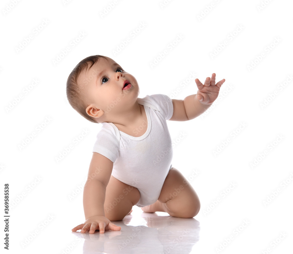 Portrait of sweet cute baby boy toddler in white body crawling on floor with hand raised and looking up