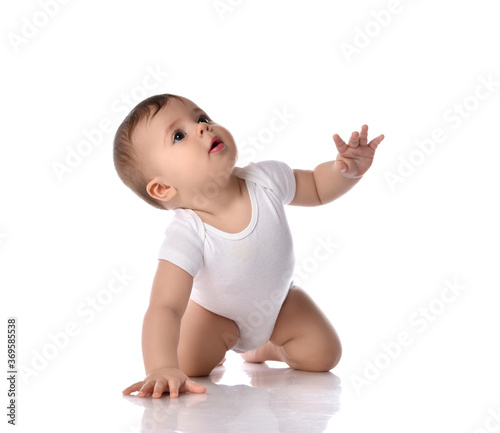 Obraz na płótnie Portrait of sweet cute baby boy toddler in white body crawling on floor with hand raised and looking up w salonie