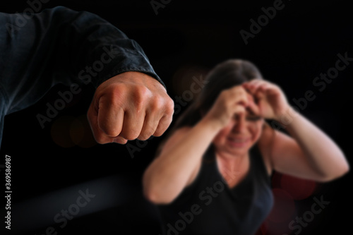 big male fist of aggressive man threatens crying woman, hits her, concept of psychological gaslighting, beating, domestic violence