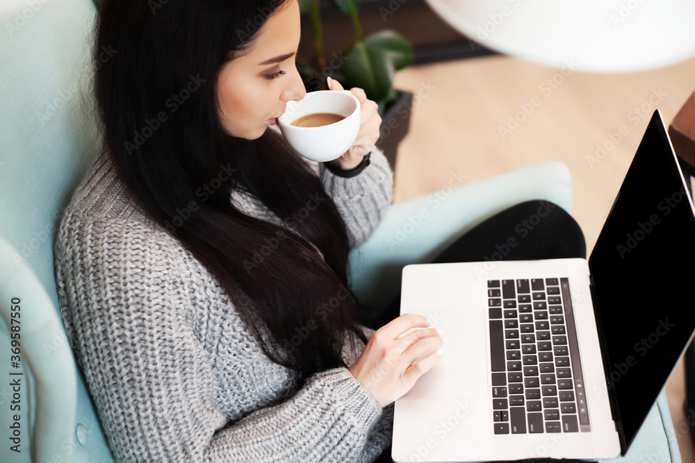 Woman in casual clothing using laptop and smiling while working indoors Woman in casual clothing using laptop and smiling while working indoors