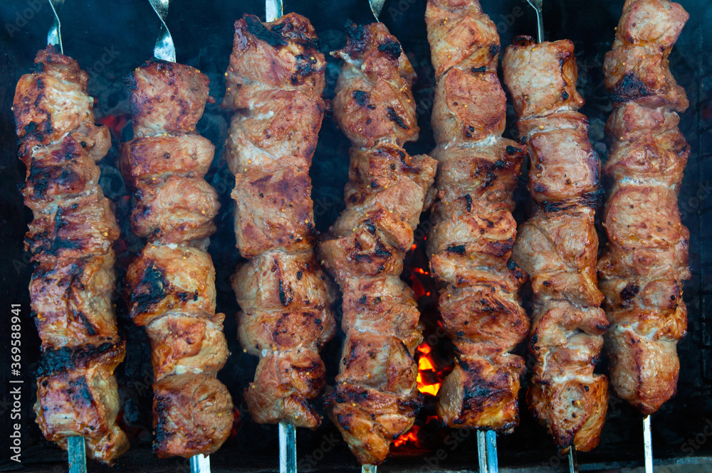 pork kebab on skewers is grilled over charcoal, smoke over a barbecue, the last degree of cooking, close