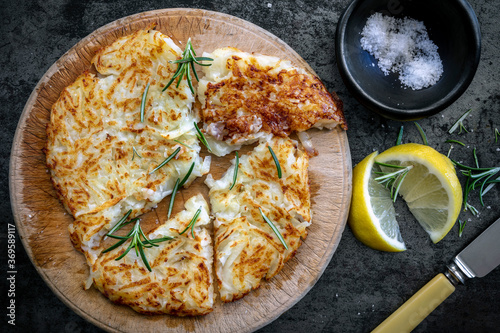 Potato Rosti on old Board with Salt Lemon and Herbs Top view