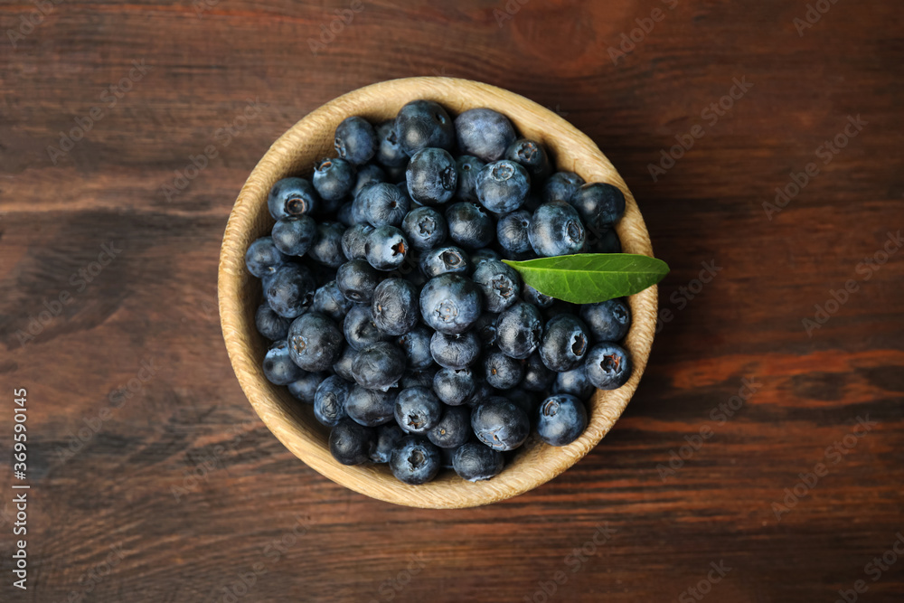 Tasty ripe blueberries in bowl on wooden table, top view Tasty ripe blueberries in bowl on wooden table, top view