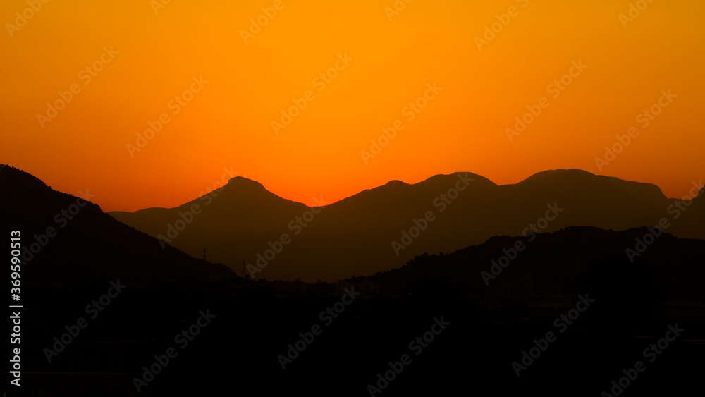 Sunset mountains. Background with orange sky and mountains

