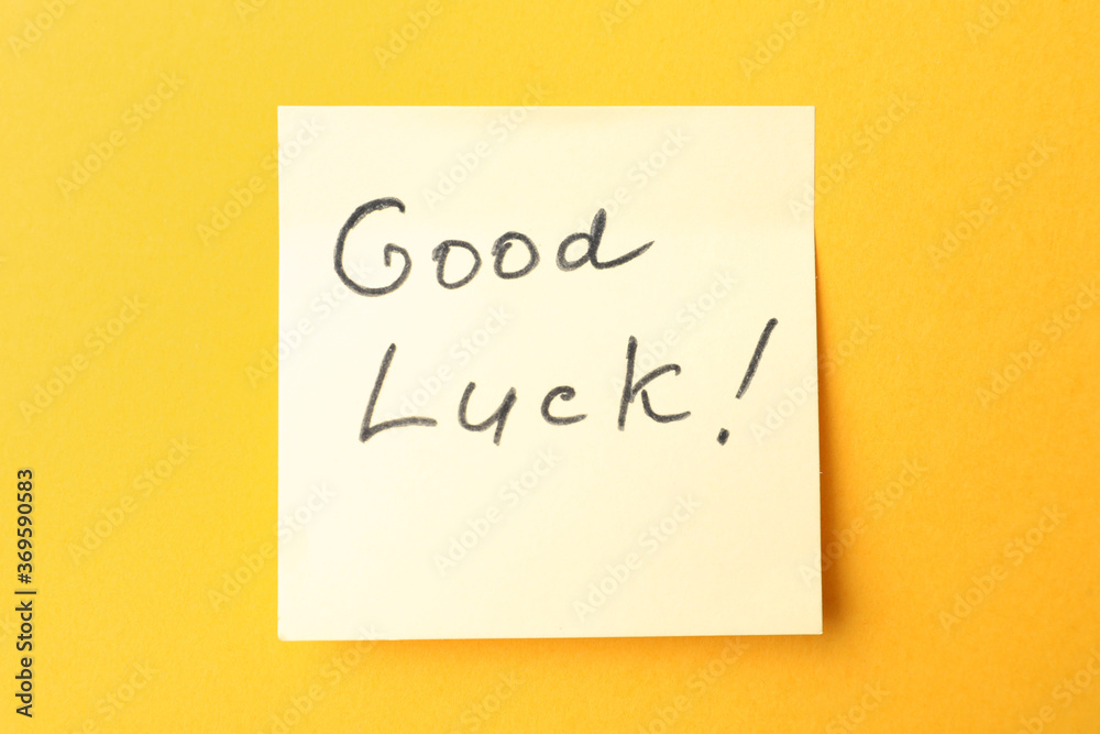 Note with phrase GOOD LUCK on orange background, top view Note with phrase GOOD LUCK on orange background, top view