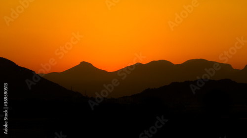 Sunset mountains. Background with orange sky and mountains
