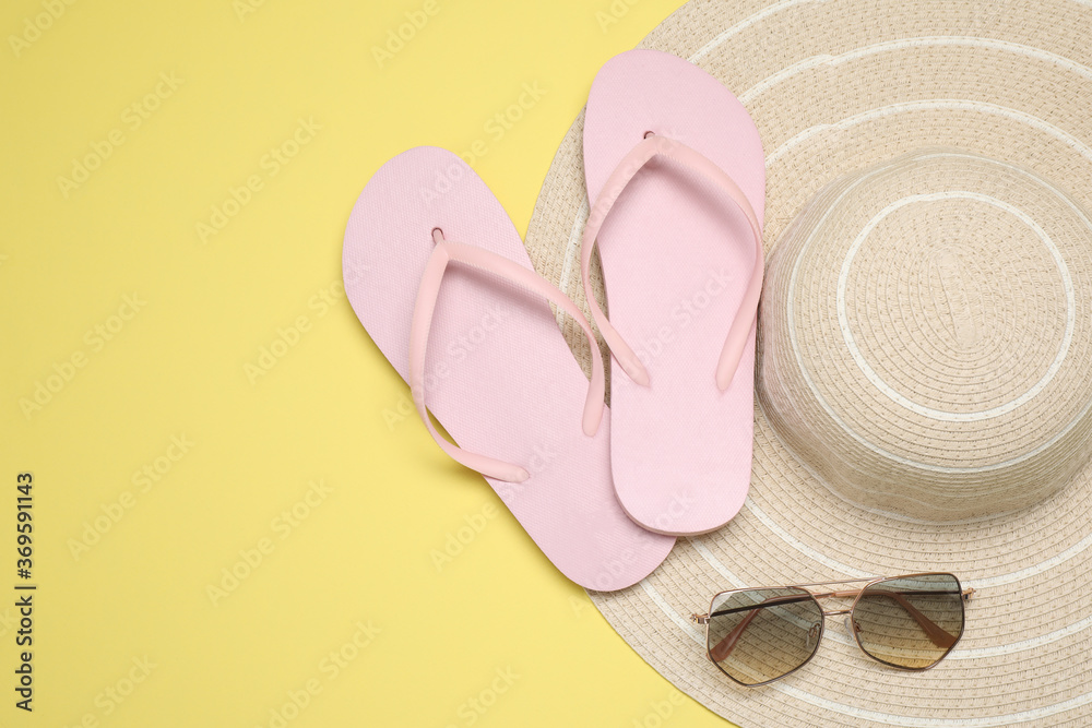 Flip flops, hat and sunglasses on yellow background, flat lay with space for text. Beach objects Flip flops, hat and sunglasses on yellow background, flat lay with space for text. Beach objects