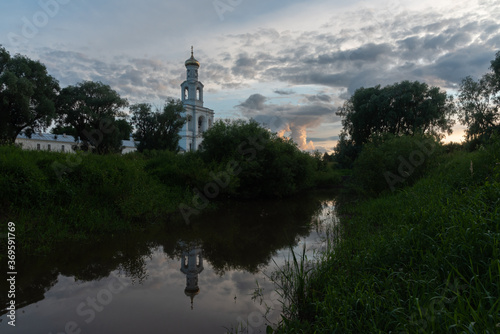 Veliky Novgorod. Yuryev Monastery. The bell tower and its reflection in the river. Summer view.Great Novgorod