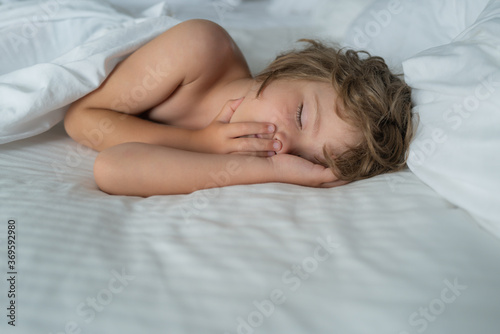 Healthy kids boy, sweetest blonde toddler kids sleeping in bed. Bedding linen and mattress in bedroom.