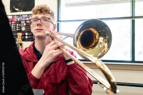 Portrait of teenage boy playing trombone in music class