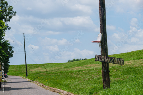 Toy plastic basketball goal and slow zone sign on utility pole along the Mississippi River levee and street in the Holy Cross neighborhood of New Orleans