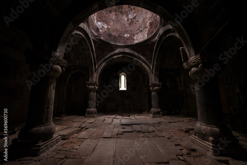 Interior of old Sanahin Armenian Monastery of the Armenian Apostolic Church with ray of light entering through narrow window and headstones on uneven ground