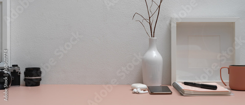 Pink worktable with stationery, smartphone, camera, accessories, decorations and copy space