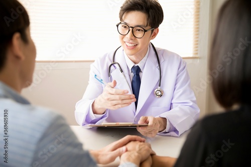 Asian male doctor consulting with couple