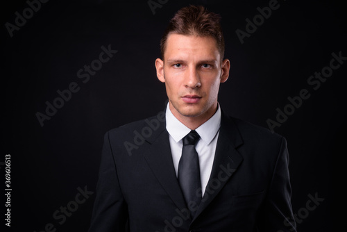 Portrait of businessman in suit against black background © Ranta Images