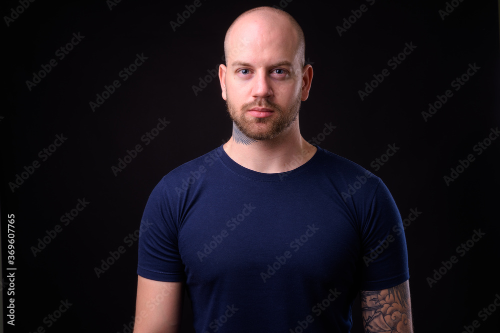 Handsome bald bearded man against black background