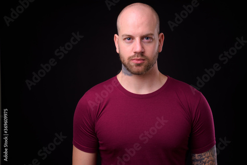 Handsome bald bearded man against black background © Ranta Images