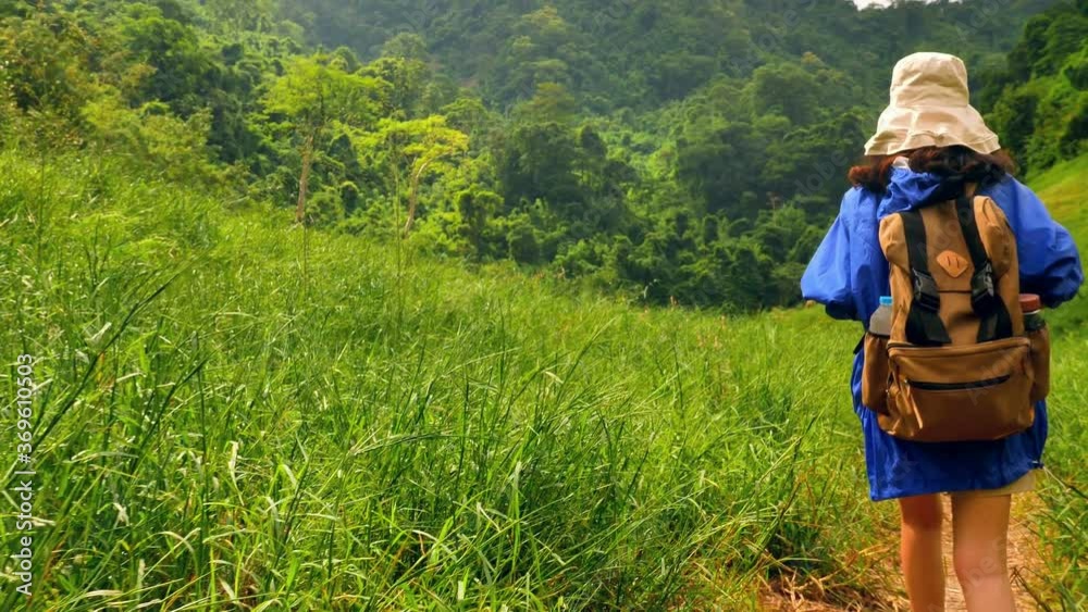 Young Asian female traveler is hiking in beautiful scenery of mountains and green fields. Young Asian female traveler is hiking in beautiful scenery of mountains and green fields.