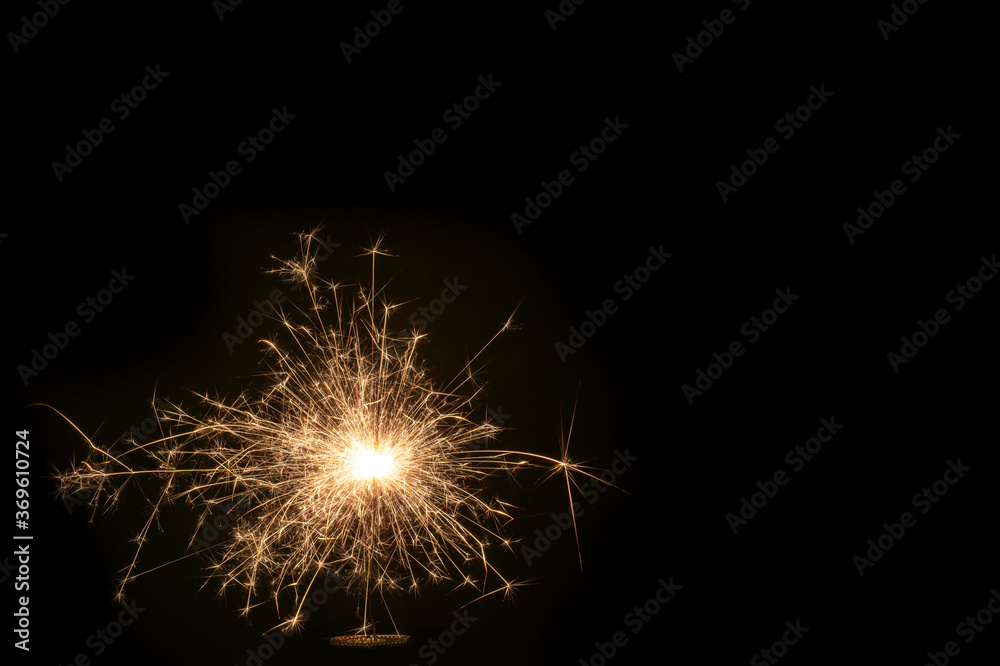 Christmas and New Year party sparkler on black burning colored sparkler on a black background, copy space