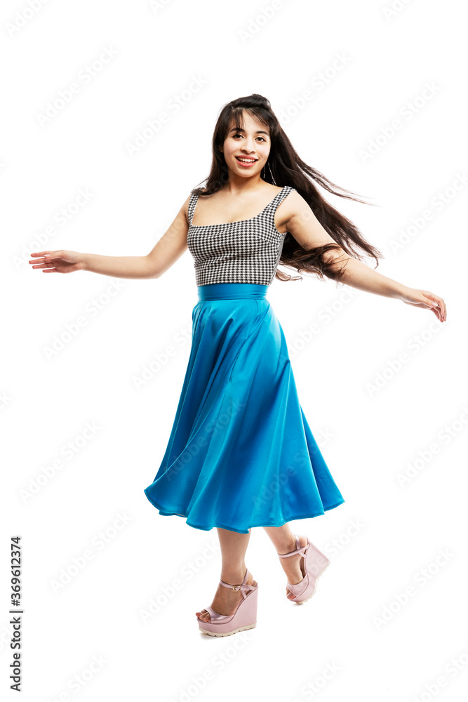 The dancing young girl. Smiling brunette with long hair in a long blue skirt. Isolated on white background. Vertical. The dancing young girl. Smiling brunette with long hair in a long blue skirt. Isolated on white background. Vertical.