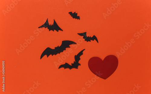 Red heart with bats and spiders on orange bright background. Halloween theme. Top view