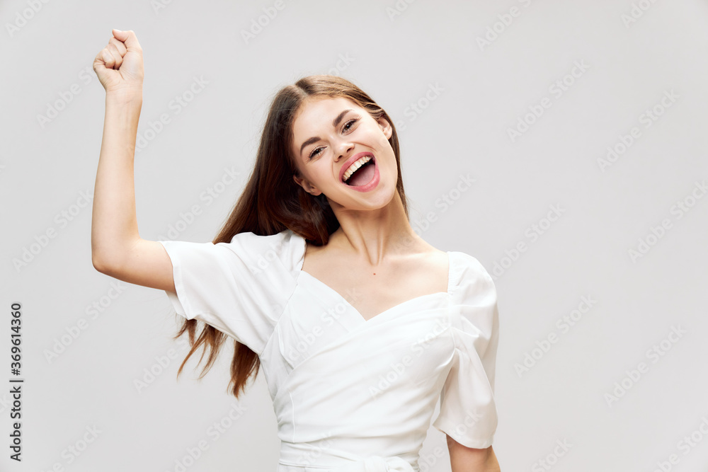 Cheerful woman with wide open mouth holds a hand above her head white dress Cheerful woman with wide open mouth holds a hand above her head white dress