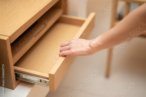 Woman hand pull open drawer wooden cabinet.