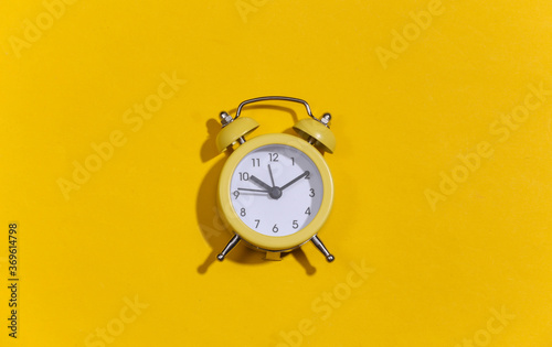 Yellow retro alarm clock on a yellow bright background. Top view. Minimalism