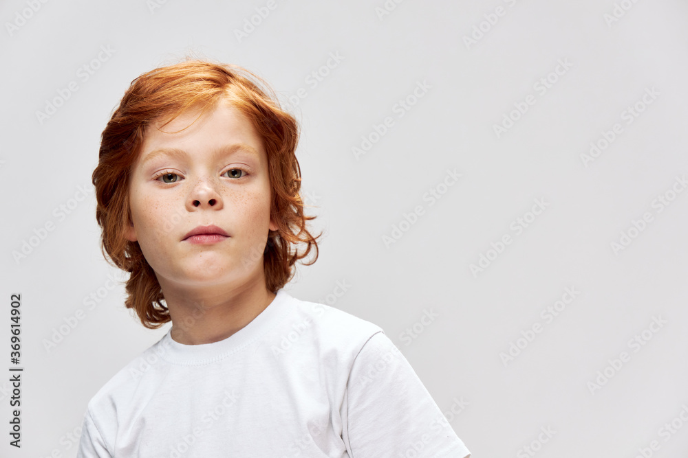 cute red-haired boy with freckles on face wearing white t-shirt gray isolated background cute red-haired boy with freckles on face wearing white t-shirt gray isolated background