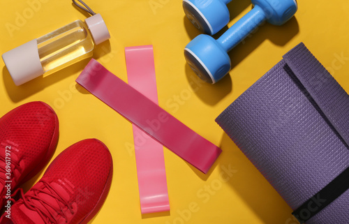 Flat lay fitness composition. Sports equipment on a bright yellow background with deep shadow. Top view