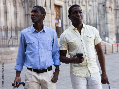 Happy travellers with suitcases visiting sights of European city © JackF