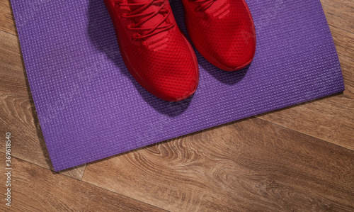 Red sport shoes and fitness mat on wooden floor. Workout concept. Top view © splitov27