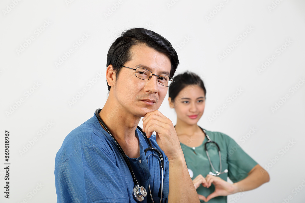 Young Asian male female doctor wearing apron uniform tunic stethoscope look at camera hart hand sing Young Asian male female doctor wearing apron uniform tunic stethoscope look at camera hart hand sing