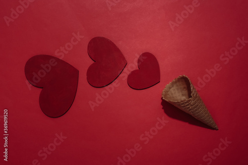 Ice cream waffle cone with hesrts on red bright background. Romantic flat lay. Top view photo