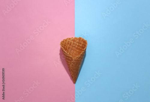 Ice cream waffle cone on pink and blue bright pastel background with deep shadow, top view. Flat lay minimal composition
