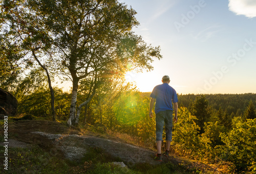 Young man walking on rock with tree with sun rays shine. Ore mountain, Czech landscape © Space Creator