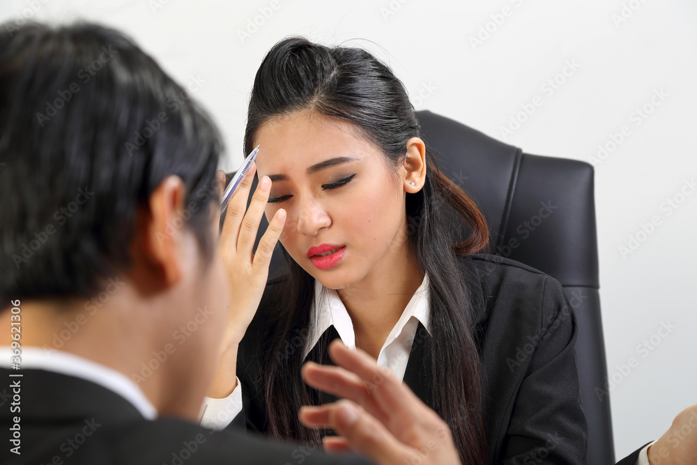 Young Asian male female wearing suit sitting at office desk thinking Young Asian male female wearing suit sitting at office desk thinking