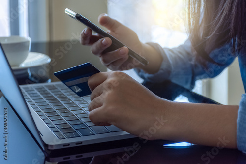 Fényképezés Woman paying and shopping by using credit card and mobile smart phone with laptop computer on the desk at home office