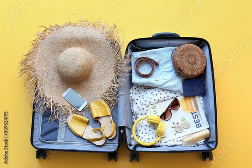 Packed suitcase with belongings on color background. Travel concept photo