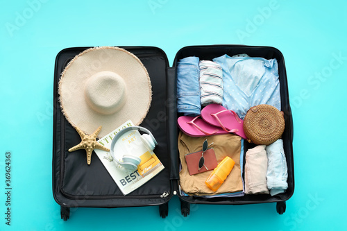 Packed suitcase with beach accessories on color background. Travel concept photo