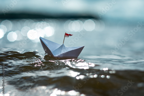 Kleines Papierschiff auf glitzerndem See photo