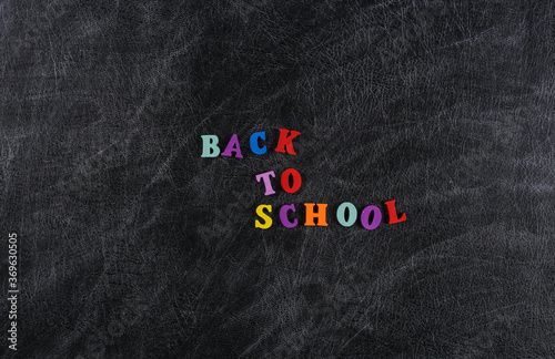 Text back to school from colored letters on a chalk board background.