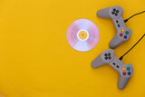 Retro gamepads, cd's on yellow background. Retro gaming. Stereo Video game, 80s. Top view. Flat lay